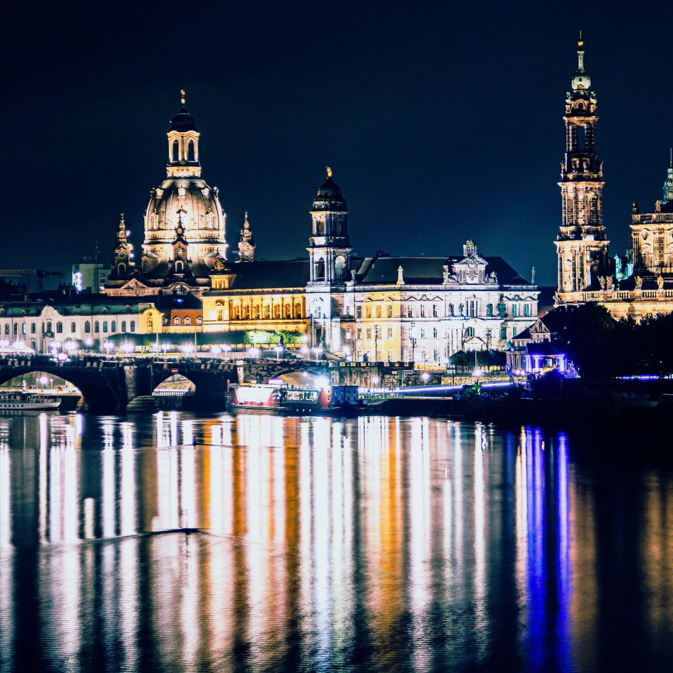 Blick vom Elbufer bei Nacht auf die erleuchtete Stadt mit Frauenkirche in Dresden