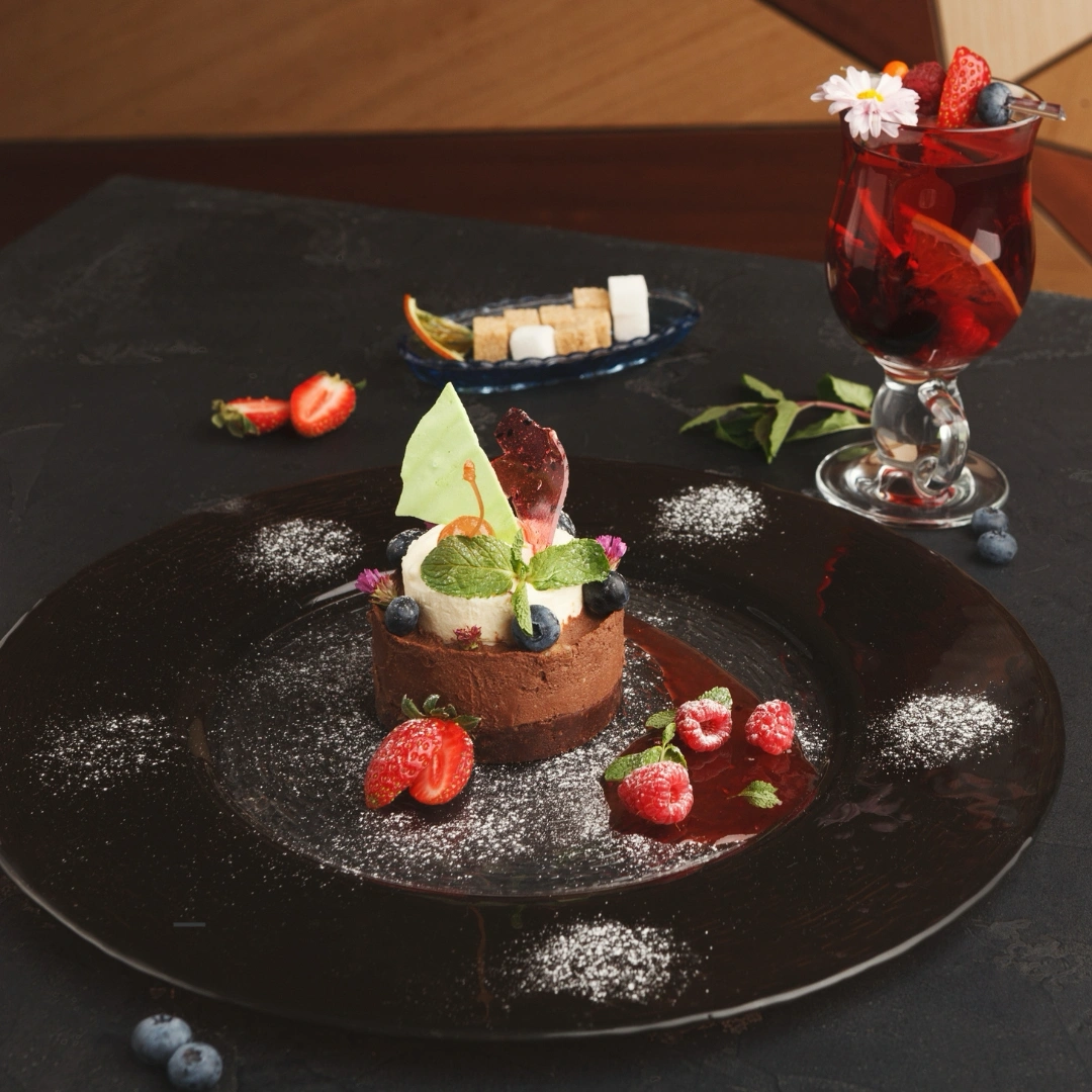 A plate with a chocolate desert on top with ice cream and decorated with berries