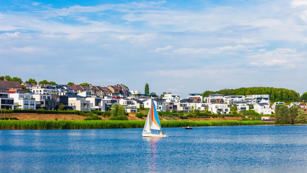 Boart with sails on a lake and houses in the background