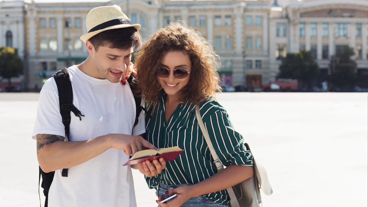 Man and Woman with bagpacks looking in a book